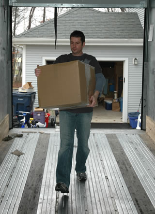A helper carrying a box up the ramp into the trailer